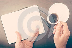 Man drinking coffee and checking his notebook