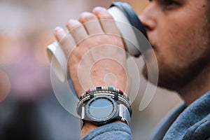 man drinking coffee from disposable cup smart watch with bracelet on wrist