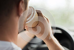 Man drinking coffee while driving the car