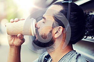 Man drinking coffee from paper cup on street