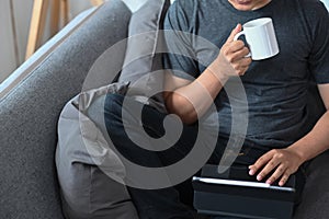 Man drinking coffee and reading email on computer tablet.