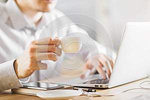 Man drinking coffee using laptop