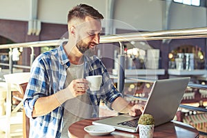 Man drinking coffee and using laptop in cafe