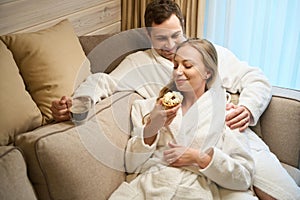 Man drinking coffee and watching his girlfriend eating tasty cake