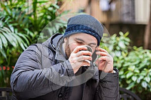 Man drinking from a cup and talking on the phone