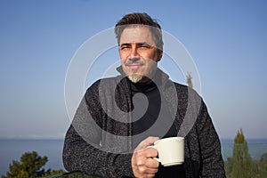 Man drinking morning coffee on balcony at home