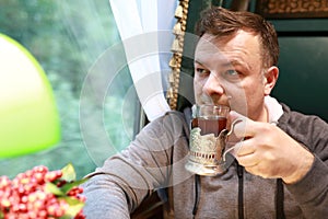 Man drinking tea in train compartment