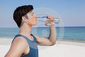 Man drinking water from bottle at beach