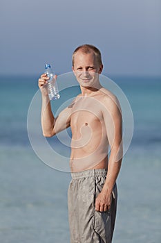 Man drinking water from a bottle on the beach portrait