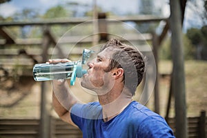 Man drinking water from bottle during obstacle course