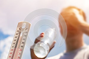 Man drinking water in extreme heat, Thermometer in summer day shows or indicate high temperature