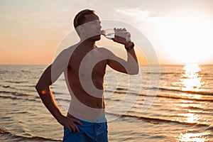 Man drinking water after his workout on the beach