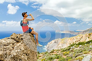 Man drinking water on rock overlooking Mediterranean Sea, Crete Island, Greece