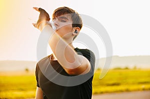 Man drinking water after running workout at beach. Thirsty healthy male with fit body drinking water.