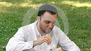 Man drinking water sitting in a beautiful green field on a sunny day