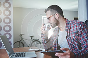 Man drinking water and working with digital tablet