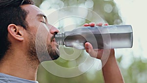 Man drinking water after workout and running outside, being healthy and hydrated. Portrait of male taking a sip of water