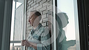 A man drinks coffee in the morning on the porch at home. He is very sad because he has a lot of problems.