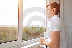 Man drinks cup of coffee on balcony overlooking forest