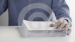 Man Drinks a Cup of Coffee and Works with a Stack of Documents at the Office Desk