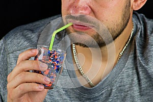 The man drinks a glass full of crushed plastic pieces.