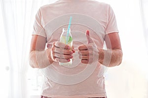 Man drinks lemonade through a straw from glass bottle