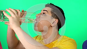 The man drinks water from a large glass.