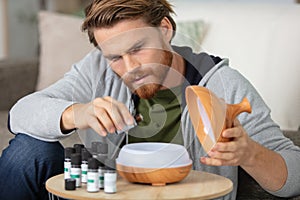 man drips essential oil into aromatherapy diffuser