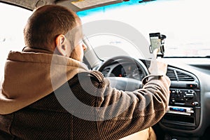 Man driver in car touching by hand smartphone screen with application navigation system