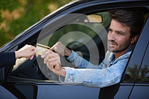 man driver giving credit card while sitting in car