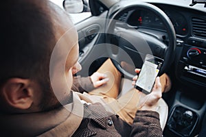 Man driver holding mobile phone with gps application in his car, modern navigation technology for travel and driving concept