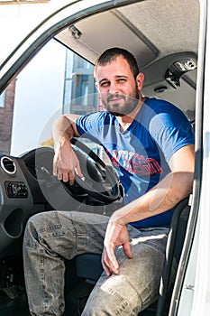 A man driver is sitting in the cab of a modern truck.