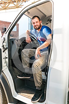 A man driver is sitting in the cab of a modern truck.