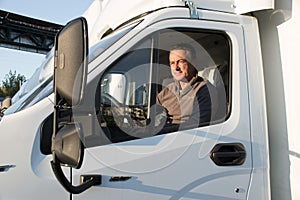 A man driver is sitting in the cab of a modern truck