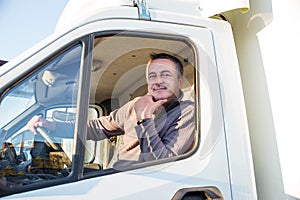 A man driver is sitting in the cab of a modern truck