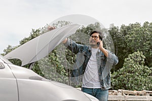 Man driver is using a mobile phone to call for help after car breakdown.