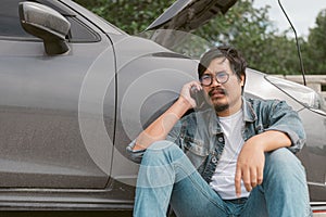 Man driver is using a mobile phone to call for help after car breakdown.