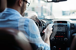 Man driver using smart phone on road in car