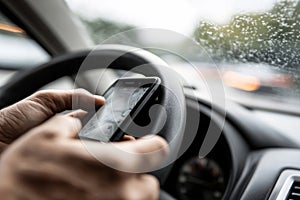 Man driver is using smartphone while driving car. Dangerous behavior, accident risk, driver distraction concept