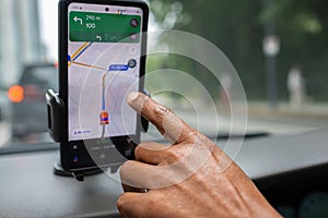 Man drives a car using a GPS navigation system on his mobile phone while driving. Male hand and smartphone in a car