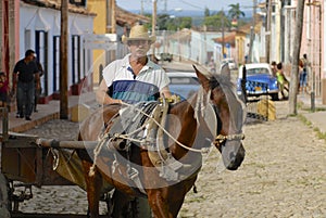 Man drives horse driven carriage at the street of Trinidad town, Cuba.