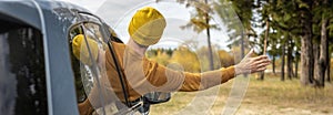 Man is driving a car along a river and forest, enjoying the silence, sunlight and beautiful autumn nature