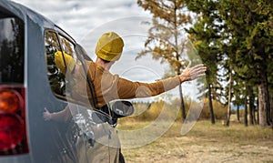 Man is driving a car along a river and forest, enjoying the silence, sunlight and beautiful autumn nature