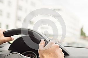 Man driving car in city. Driver holding steering wheel.