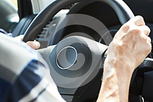 Man driving car, close-up. Driver hands holding steering wheel