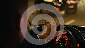 Man driving car fast in night city street with traffic. Road trip, driver concept. Commuter, male taxi cab driver. Back