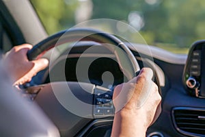 A man driving a car firmly holds on to the steering wheel with his hands. Driving a car on a weekend trip