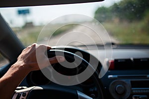 A man driving a car, focus on the left hand held on steering wheel