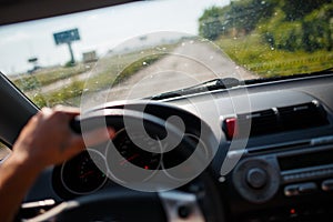 A man driving a car, focus on the left hand held on steering wheel