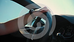 Man driving car. Hand on the steering wheel against the background of the road on sunny day. Close up